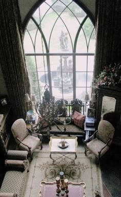 a living room filled with furniture next to a large arched window and lots of windows