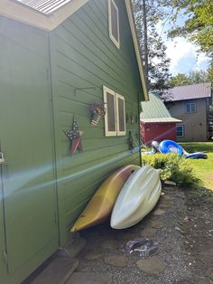 two canoes leaning against the side of a green house