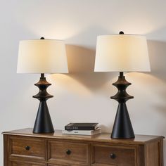 two lamps sitting on top of a wooden dresser