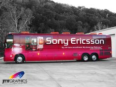 a red bus parked in front of a building with trees behind it and the words sony ericson on the side