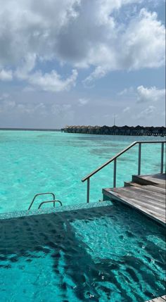 the water is very clear and blue with some steps going down to the beach in front of it