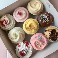 a box filled with lots of different flavored cupcakes