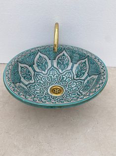 a blue and white bowl sink with gold faucet in the center on a tile floor