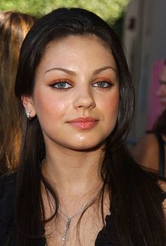 a close up of a woman with long hair and blue eyes wearing a black top