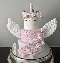 a three tiered cake decorated with pink roses and an angel's wings