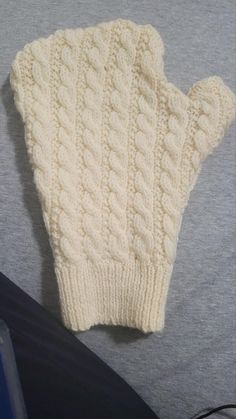 a white knitted mitt laying on top of a table