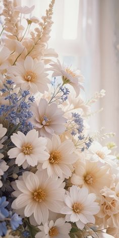 a bouquet of white and blue flowers sitting on top of a table next to a window