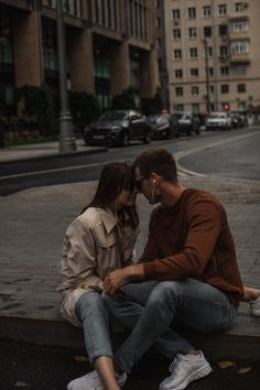 a man and woman sitting on the curb next to each other