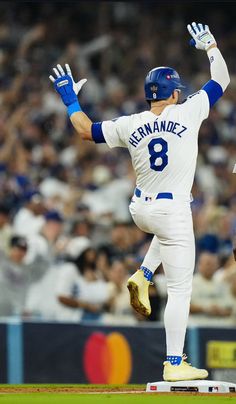 a baseball player with his arms in the air while standing on top of a base