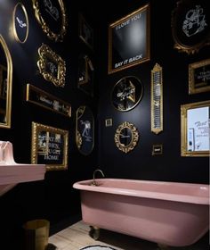 a pink bath tub sitting next to a white sink in a room filled with framed pictures