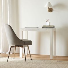 a desk with a chair and clock on it in front of a window that says west elm