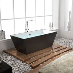 a bath tub sitting on top of a wooden floor next to a white rug and window