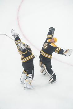 two hockey players in black and yellow uniforms on the ice with their arms out to each other