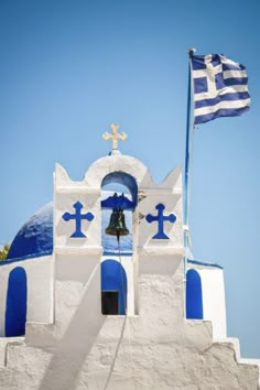 a blue and white church with a flag flying in the wind next to it's bell tower