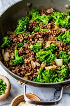 broccoli, onions and ground beef in a skillet on a marble counter