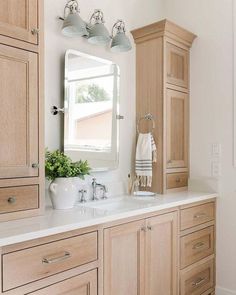 a white sink sitting under a bathroom mirror next to a wooden cabinet and counter top