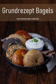 a basket filled with bagels and dips on top of a wooden table next to bread