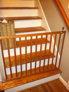 there is a basket sitting on the top of some stairs in this house with wood handrails