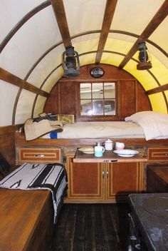 the inside of a small room with two beds and a table in it, next to a window