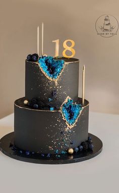 a three tiered cake with blue and black frosting on it's side