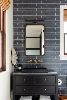 a bathroom with a black vanity and brick wall