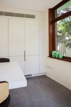 a kitchen with white cupboards and a window in the corner, next to a counter