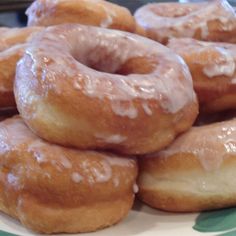 a pile of glazed doughnuts sitting on top of a white and green plate