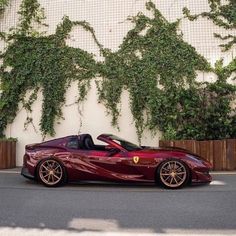 a red sports car is parked in front of a wall with ivy growing on it