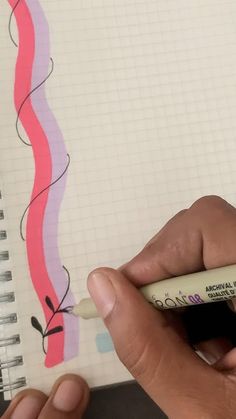 a hand holding a marker and writing on a notebook with spiral lines in the background