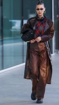 a woman walking down the street wearing brown leather pants