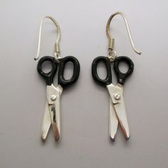 pair of black and silver scissors dangling from earwires on white surface with hook earrings