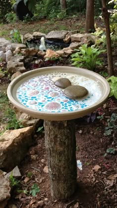 a bird bath in the middle of a garden with rocks and plants around it,