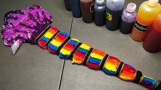 a rainbow colored tie - dye ribbon laying on the floor next to bottles of paint