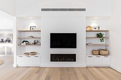 a living room with white walls and wooden flooring, built in shelving units