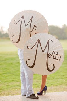 a man and woman holding umbrellas with the word mr and mrs written on them