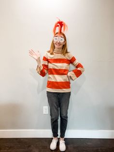 a woman wearing glasses and a striped shirt is standing in front of a white wall