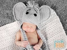 a baby wearing a knitted elephant hat and diaper is wrapped in a blanket