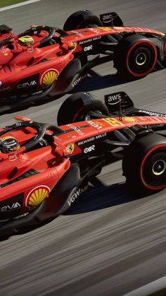 two red race cars driving on a track with one behind the other in front of another