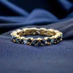 a gold ring with blue sapphire stones on a black cloth background, close - up