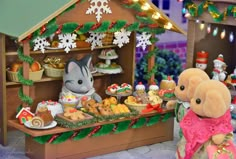 two stuffed animals are standing in front of a toy house with christmas decorations on it