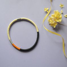 two bracelets sitting on top of a table next to flowers and a yellow ribbon