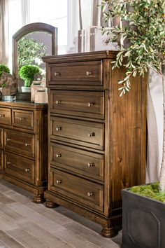 a bedroom with a dresser and mirror next to a potted plant on the floor