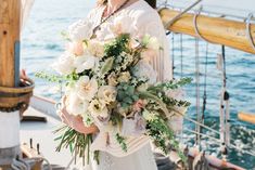 a woman holding a bouquet of flowers on top of a boat