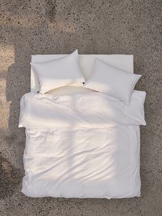 an overhead view of a bed with white sheets and pillows