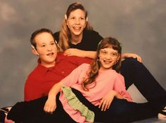 three children sitting on the floor with their arms around each other and smiling at the camera