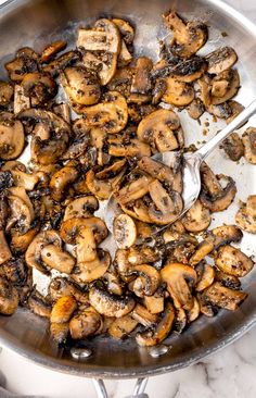 mushrooms are being cooked in a pan with spoons