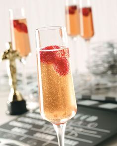 two champagne flutes filled with liquid and topped with raspberries, sitting on a table