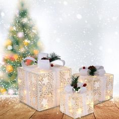 two white gift boxes sitting on top of a wooden floor next to a christmas tree