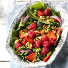 a salad with strawberries and nuts in a bowl