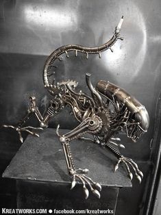 a metal sculpture of an alien sitting on top of a table